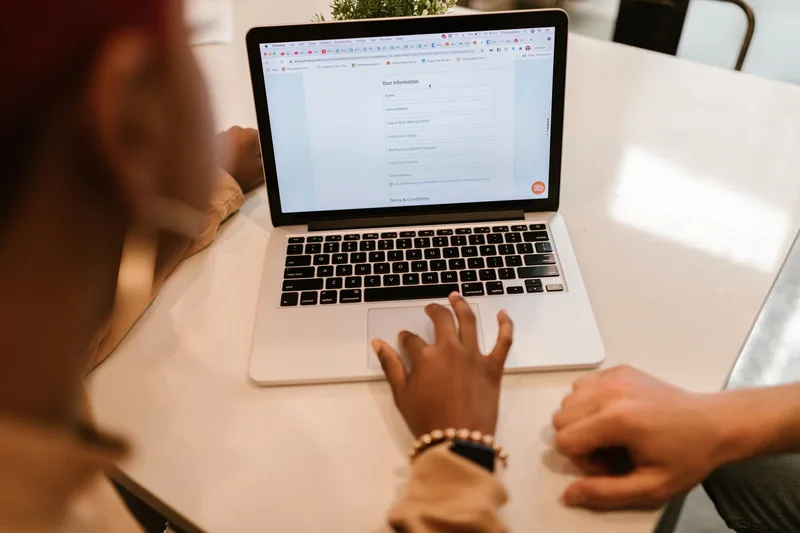Two adults working together over a laptop showing an online form, demonstrating a simple survey fill-in flow