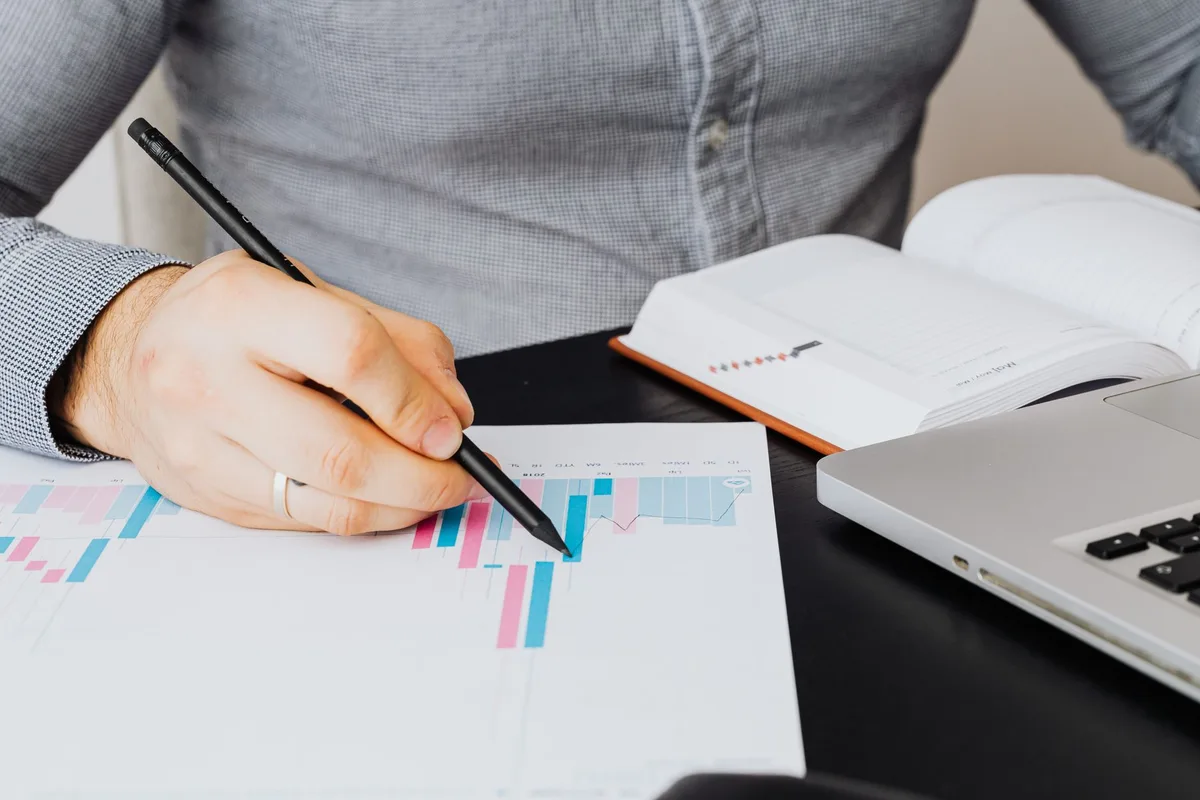 A solopreneur reviewing survey responses on a laptop, with a Google Sheets spreadsheet open showing patterns in customer feedback