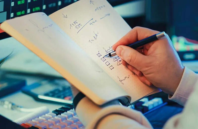Person writing a target customer profile in a notebook