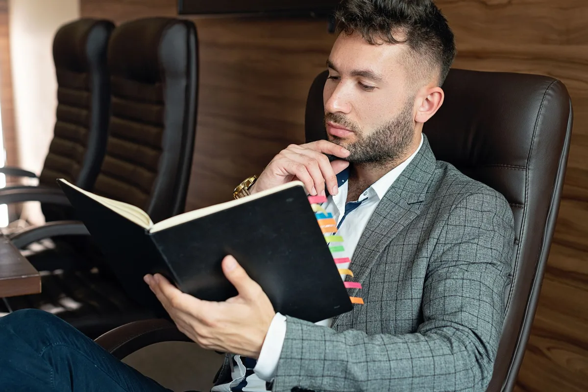 Entrepreneur at desk reviewing multiple business idea notes spread across a notebook