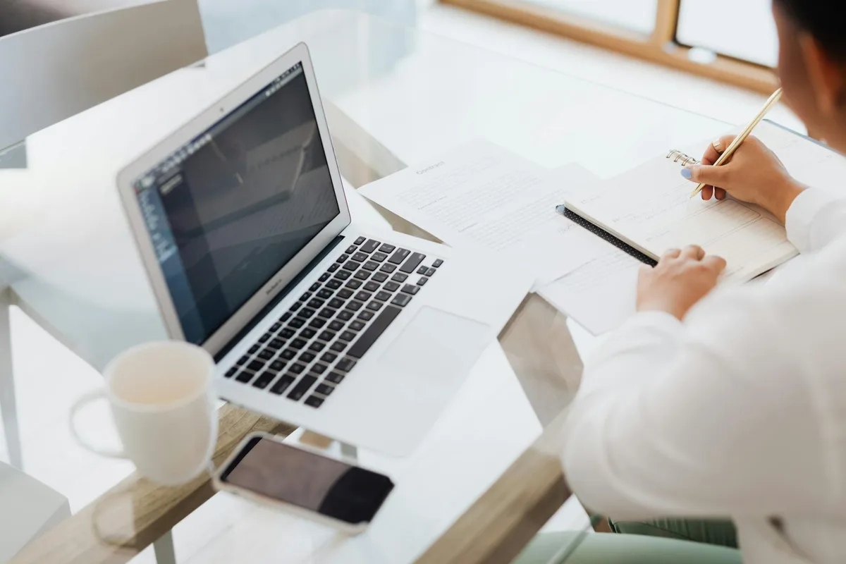 A solopreneur working through an idea evaluation at a desk with a notebook and laptop